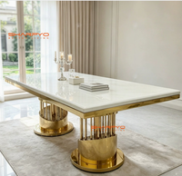 Table à manger moderne de luxe en métal avec plateau en pierre frittée marbrée et pieds en acier inoxydable créatifs pour mobilier de salle à manger d'hôtel