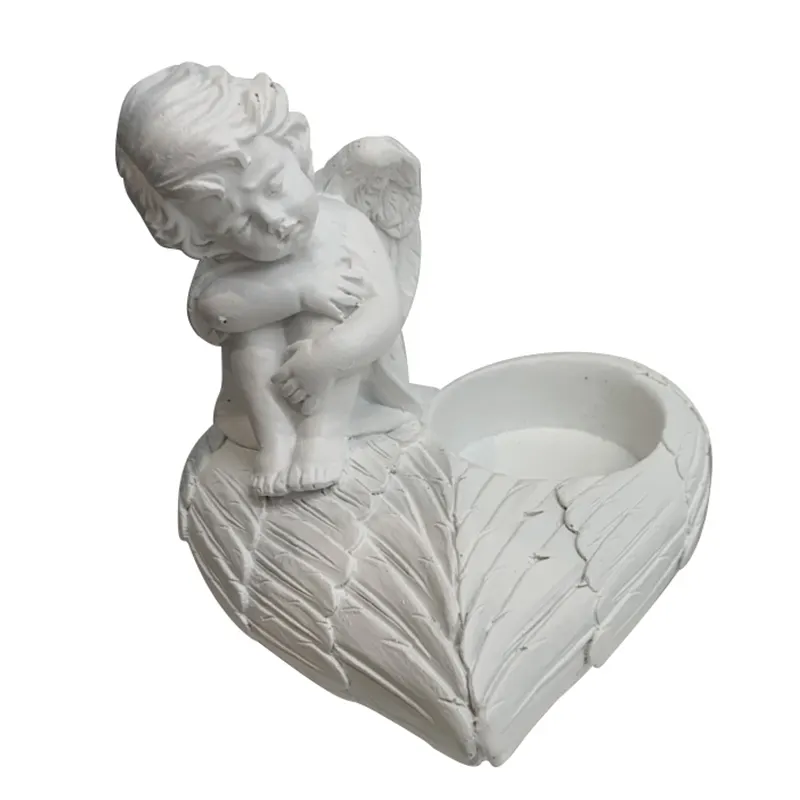 ハート型の石の記念キャンドルホルダーに座っている白い樹脂の祈りの翼の天使