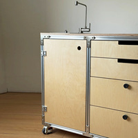 Meuble de cuisine mobile en profilé aluminium et contreplaqué marin, avec évier, tiroirs et roulettes, servant également de bar à café et d'îlot.