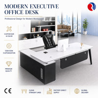 Bureau de direction moderne noir et blanc contrasté avec pieds métalliques inclinés, passe-câbles rond, armoire latérale, table de PDG/directeur