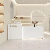 Comptoir de réception moderne en bois MDF avec éclairage LED, finition or, blanc et rose, forme oblongue, mobilier commercial pour hôtel, bar, centre commercial
