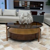 Table basse ronde moderne à deux niveaux avec surface en verre ambré, pieds en métal cuivré et base en bois à motif étoilé