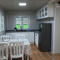 Maison conteneur moderne à toit en pente extensible 20 pieds, finition blanche, 2 chambres, 1 séjour, fenêtres en treillis, porche avant, chalet clé en main