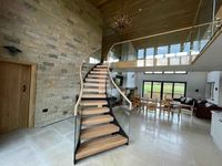 Escalier courbé avec rampes en acier inoxydable revêtu de noir et marches en bois massif, pour usage intérieur, design contemporain durable