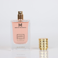 Parfum féminin, flacon rectangulaire en verre transparent, liquide rose, capuchon doré à nervures, boîte à ruban, parfum floral aux pétales