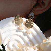 Boucles d'oreilles créoles motif feuille tropicale, en laiton artisanal, design ajouré, avec feuilles de bambou évoquant une coquille de tortue et pierres turquoise. Oreille