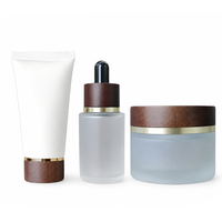 Ensemble de flacons cosmétiques en verre givré de luxe avec bouchon en bois de noyer et anneau doré pour des solutions complètes d'emballage de soins de la peau