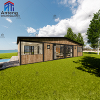 Maison préfabriquée en conteneur extensible en forme de L, résistante aux intempéries, avec finition en bois foncé et fenêtres du sol au plafond