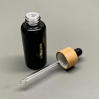 Vente en gros de flacons compte-gouttes en verre noir brillant de 30 ml avec compte-gouttes en bambou et impression sérigraphique pour les gouttes pour les yeux et les sérums pour le soin de la peau