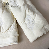 Veste en duvet d'hiver blanc pur de style designer, manteau en duvet court à col en laine avec capuche pour femme avec broderie personnalisée