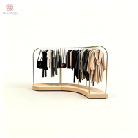 Porte-vêtements en métal doré incurvé avec base en bois clair, support de présentation pour vêtements, présentoir pour boutique de vêtements, pour magasin de vente au détail