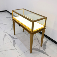 Vitrine de présentation de bijoux en métal doré avec comptoir en verre trempé et éclairage LED intégré pour la vente au détail de bijoux, montres, bagues et colliers