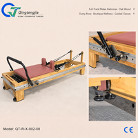 Reformer de Pilates en bois de chêne rose poussiéreux avec barre de pieds intégrée et barre spécialisée pour cours de bien-être en boutique