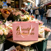 Sac cadeau en papier rose clair avec poignée en ruban de satin et impression dorée, élégant sac de transport pour boutique, produits de beauté, vente au détail et événements.