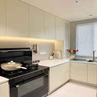 Meuble de cuisine en bois gris mat sur mesure en forme de L avec lave-vaisselle encastré, appareils électroménagers noirs, plan de travail blanc, moderne et écologique CARB P2
