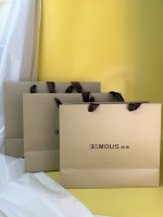Sacs shopping en papier de luxe personnalisés avec impression couleur, logo en feuille d'or noir, lignes en relief et poignées en corde marron