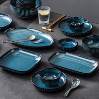 Service de table en céramique bleu réactif avec glaçure de four et rayures verticales, comprenant bol, assiette et plat de service