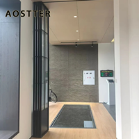Porte pliante AOSTTER en aluminium finition noire minimaliste avec panneau de sécurité haute transparence et seuil encastré pour villa contemporaine