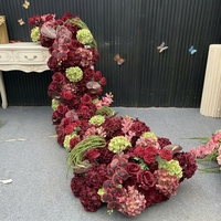 Composition florale en soie rouge bordeaux personnalisée, arche florale incurvée irrégulière avec des lianes vertes suspendues pour toile de fond de mariage d'automne