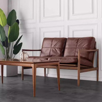 Fauteuil d'appoint en cuir et noyer de style Mid-Century, avec coussin marron à points de couture et rembourrage haute résilience, idéal pour salon ou coin lecture.