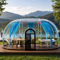 Salle ovale à dôme transparent avec rideaux bleus et vue sur le lac pour la restauration en resort et l'accueil en plein air