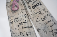 Jean baggy unisexe beige gris délavé avec imprimé graffiti intégral, coupe large, avec breloques en peluche et détails de chaînes colorées