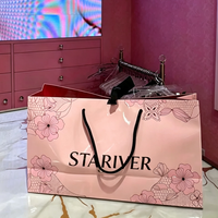 Sac en papier personnalisé imprimé rose clair avec laminage brillant, poignées en corde noire et doublure intérieure rouge pour l'emballage de vêtements féminins