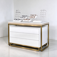 Meuble à lunettes blanc avec finition bois, cadre métallique doré, trois tiroirs, support en acrylique, pour comptoir de magasin d'optique, certifié CE ETL