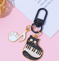 Porte-clés en alliage de zinc avec motif de petit chat noir musical de dessin animé et notes de piano, accessoire de sac mignon et original pour hommes et femmes