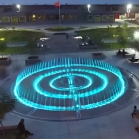 Fontaine musicale circulaire à jet sec pour extérieur, avec jets interactifs au sol et éclairage LED cyan, idéale pour les places publiques