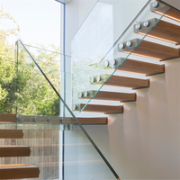 Escalier flottant minimaliste avec marches en bois et balustrade en panneaux de verre transparent