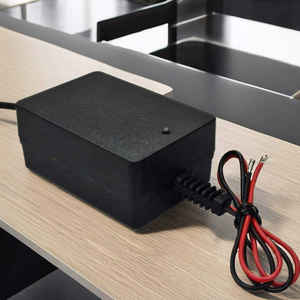 Adaptateur d'alimentation noir avec câble connecté et fils apparents placés sur une surface de bureau moderne dans un espace de travail intérieur - Product Image 1