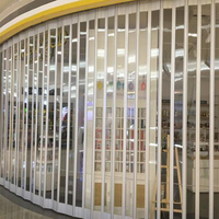 Porte pliante moderne en alliage d'aluminium avec cadre incurvé en cristal, cloison transparente sur mesure pour les intérieurs de centres commerciaux et de magasins