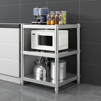 Estante de almacenamiento de cocina de acero inoxidable con tres niveles de estanterías para artículos diversos y platos.