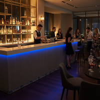 Comptoir de bar moderne en forme de L avec dessus en Corian blanc et façade gris foncé, éclairage LED RGB sous le comptoir, personnalisable pour restaurant/hôtel/club