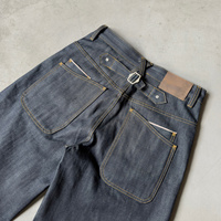 Jeans en denim brut à poche incurvée et boucle arrière, braguette boutonnée, jambe large, denim selvedge, double poche arrière, boucles croisées, jeans baggy