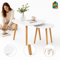 Ensemble de deux tables basses en forme de galet avec plateau blanc et trois pieds en bois, style scandinave moderne pour salon