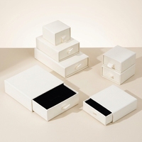 Boîte à bijoux sur mesure en blanc ivoire avec ruban de tirage pour une marque d'élite et une boutique de détail sophistiquée