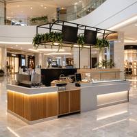 Kiosque à café moderne sur mesure pour centre commercial, comptoir de bar central avec vitrine à gâteaux en verre et support pour plantes suspendues