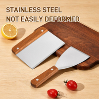 Ensemble d'ustensiles de cuisine en acier inoxydable gris avec manche en bois : spatule, pelle, poêle à frire, plaque à pizza et plaque de cuisson anti-goutte