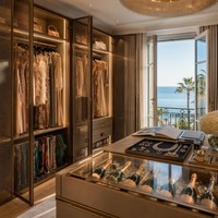 Dressing de luxe style Riviera française avec portes vitrées en treillis métallique et îlot central champagne pour suite principale de villa