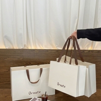 Sac fourre-tout en papier biodégradable blanc crème de luxe avec logo personnalisé, laminage mat, large ruban pour boutique de vêtements et de chaussures