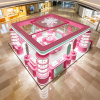 Kiosque de bijouterie rose pastel et menthe, stand modulaire avec présentoirs cylindriques éclairés par LED