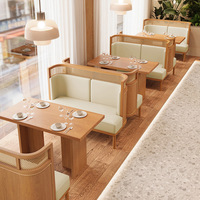 Table à manger en bois blond, chaise avec dossier en cannage tressé, siège rembourré blanc, banquette couleur sauge pour restaurant et hôtel