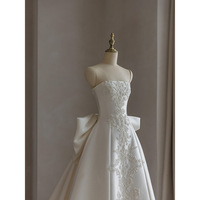 Robe de mariée élégante en satin ivoire avec appliques florales, dos lacé et traîne.