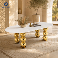 Table de banquet ovale de luxe pour hôtel, avec plateau en marbre blanc et pieds en acier inoxydable doré, pour événements et mariages.