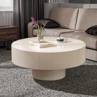 Table basse de style européen moderne, design tambour cannelé, plateau en pierre à bords embossés, structure en bois, piétement durable, table centrale blanche