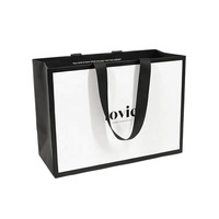 Sac en papier noir enduit de poignées de ruban intégrées avec logo en feuille d'or imprimé de luxe