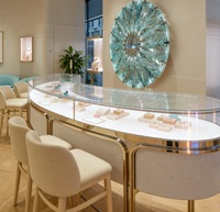 Vitrine à bijoux de luxe en forme de S, incurvée, de haute qualité et durable |   Base en pierre crème avec cadre en métal doré |   Vitrine en verre LED