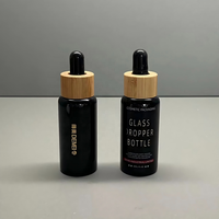 Vente en gros de flacons compte-gouttes en verre noir brillant de 30 ml avec compte-gouttes en bambou et impression sérigraphique pour les gouttes pour les yeux et les sérums pour le soin de la peau